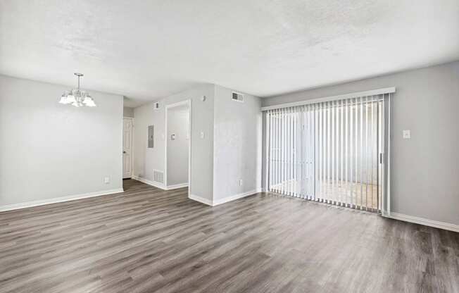 an empty living room with a sliding glass door to a balcony