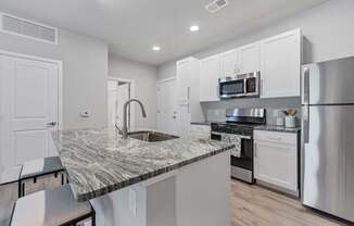 A kitchen with a marble countertop and stainless steel appliances.