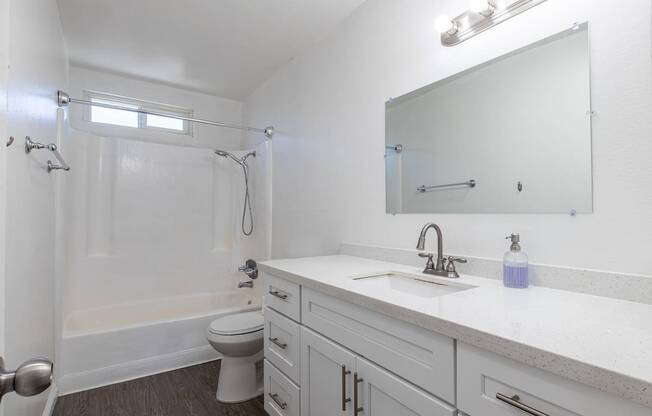 A white bathroom with a toilet, sink, and shower.