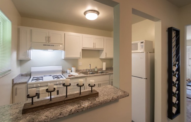 This is a photo of the kitchen with pass through breakfast bar of the 550 square foot 1 bedroom, 1 bath, balcony floor plan model apartment at College Woods Apartments in thne NOrth College Hill neighborhood of Cincinnati, OH.