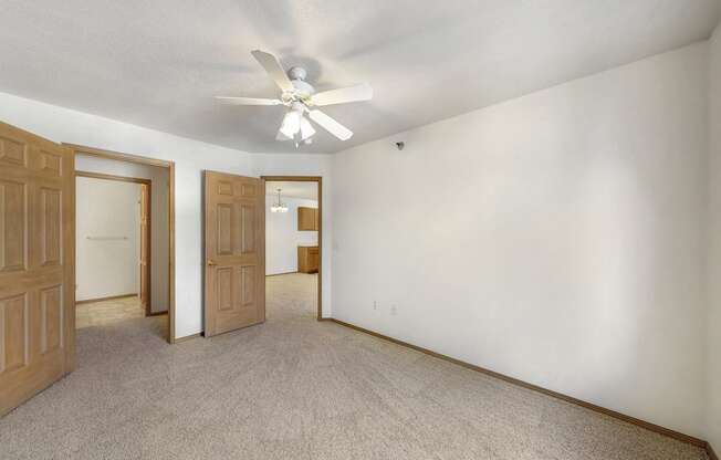 an empty living room with white walls and a ceiling fan