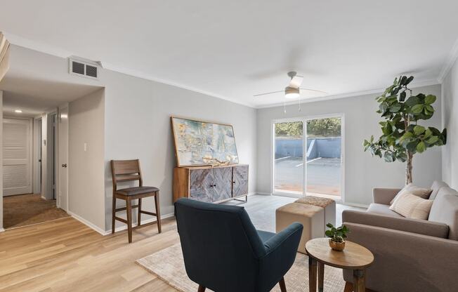 a furnished living room with warm wood floors, large windows, an illuminated ceiling fan at Mountainside Apartments