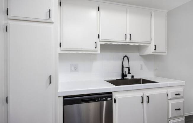 an empty kitchen with white cabinets and a sink