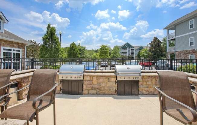 an outdoor patio with two bbqs and a stone wall