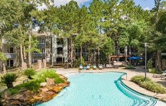 A swimming pool surrounded by trees and a building in the background.
