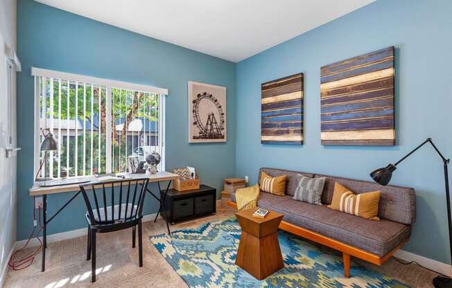 a living room with blue walls and a couch and a desk with a chair at Mullan Reserve Apartments, Montana