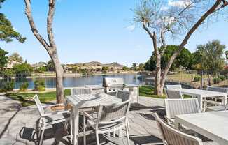 A patio with a table and chairs overlooking a lake.