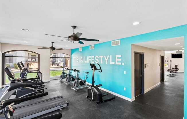 A gym with a row of treadmills and a wall that says "It's a lifestyle."