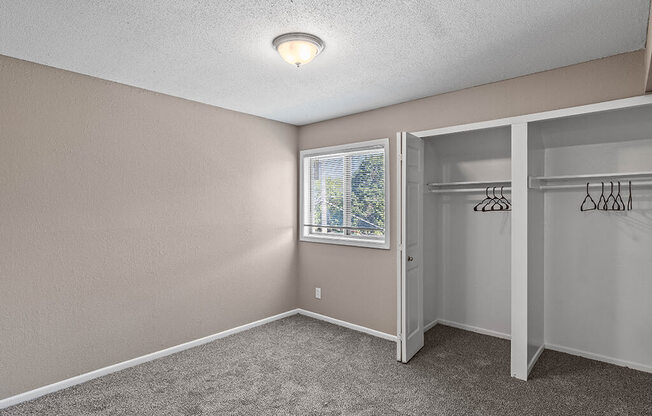 an empty bedroom with a closet and a window