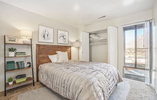 A bedroom with a large bed, a wooden headboard, and a window with a view of the mountains.