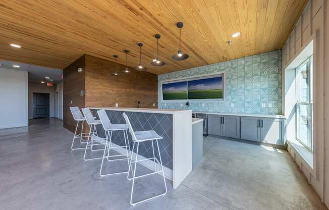 A room with a long bar and chairs.