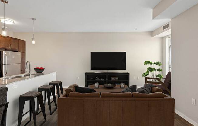 A living room with a brown couch, a television, and a plant.