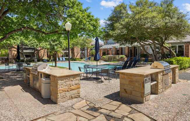 A pool surrounded by stone pillars and chairs.