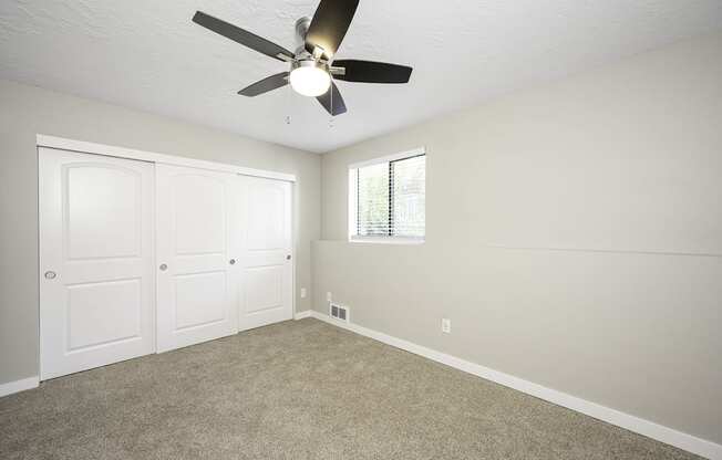 a bedroom with a ceiling fan and two closets