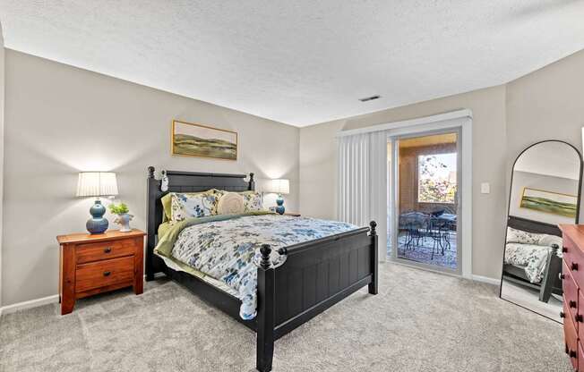 A bedroom with a large bed, a dresser, and a mirror.