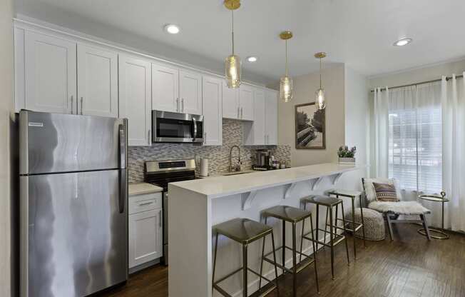 Stunning Kitchen with effieincet appliance, pendant lighting, and bar stool seating at Serra Vista Apartment Homes, Lynnwood, WA