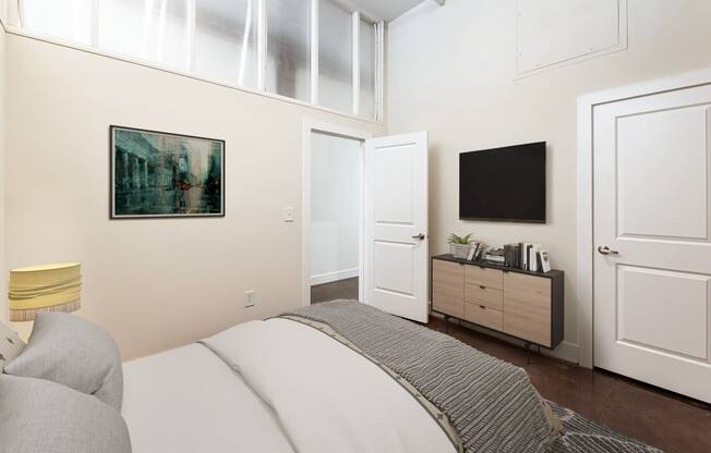 a bedroom with a bed and a tv on the wall