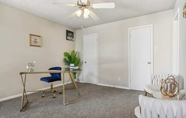 a living room with a desk and a ceiling fan