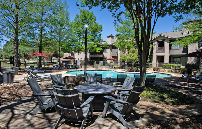 A table and chairs set is in the foreground of a pool area.