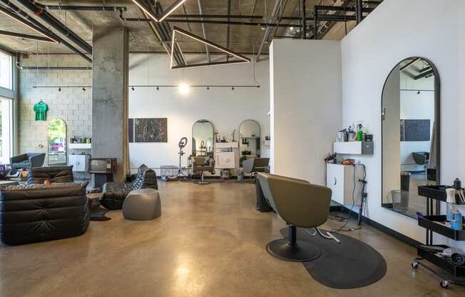 Interior of neighborhood salon with seating area and salon chairs and mirror.