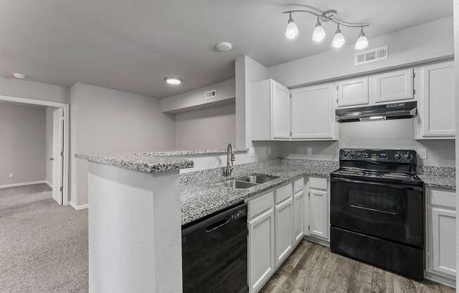 A kitchen with black appliances and white cabinets.
