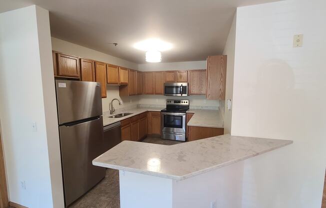 an empty kitchen with stainless steel appliances and a marble counter top