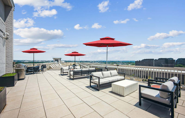 the rooftop terrace of a building with couches and umbrellas