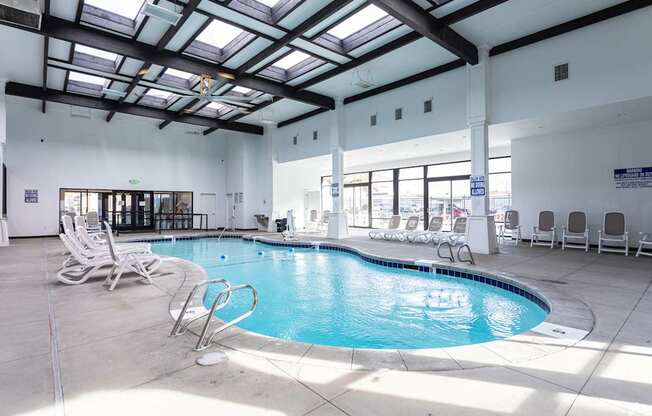 A large indoor swimming pool with sunlight streaming in through the windows.