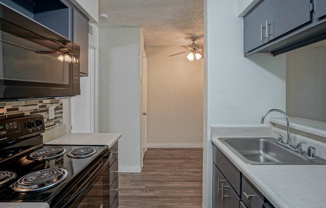 Kitchen equipped with black appliances and grey cabinets at Treehouse Apartments in Albuquerque, NM