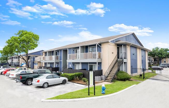 an apartment building with cars parked in a parking lot