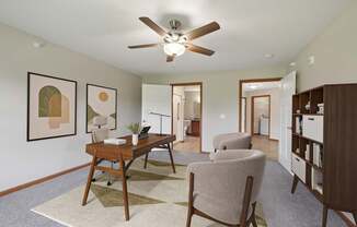 A room with a ceiling fan and a desk with a chair.