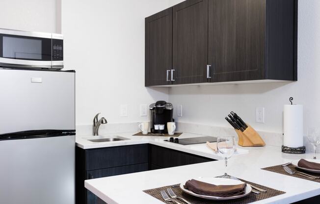 Apartments in Sunnyvale CA - mResidences Silicon Valley - Kitchen with White Walls, Silver Appliances, Dark Brown Cabinets, Silver Hardware, and White Counters