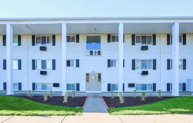 a white apartment building with a sidewalk and grass