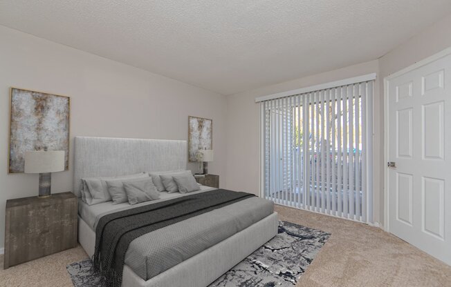 A bedroom with a large bed and a window with blinds.