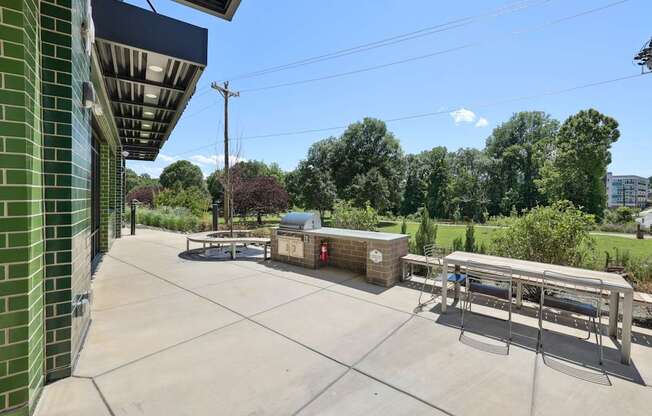A sunny day at the park with a bench and a picnic table at Link Apartments® CYKEL Apartments, Charlotte