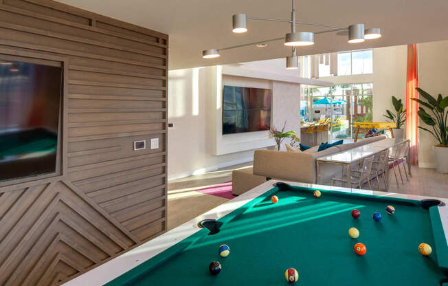 A pool table in a room with a wooden wall and a TV.
