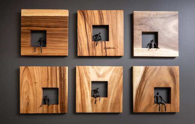 Six wooden frames with black silhouettes of people inside them.