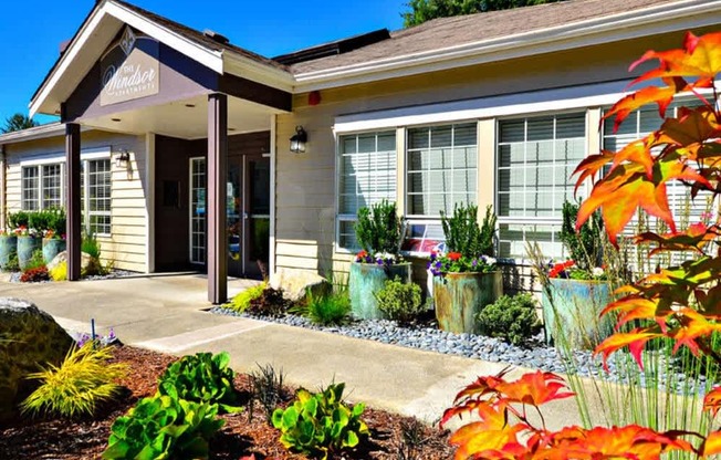 A small building with a porch and a garden in front.