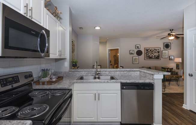 a kitchen with white cabinets and black appliances at Whitehall Estate apartments in Charlotte NC