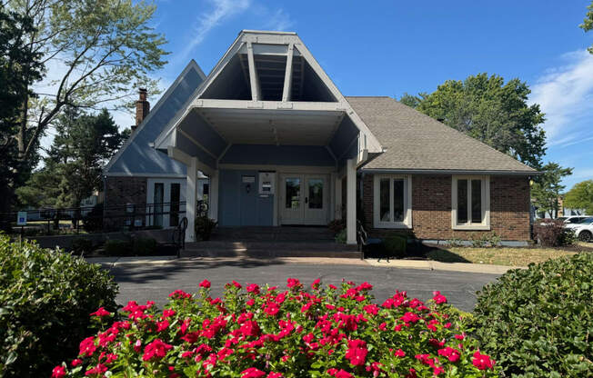 the front of a house with pink roses in the front yard