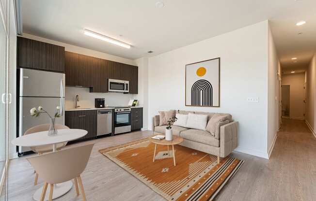 a living area with a couch table and chair and a kitchen with a stove microwave and sink at The Box, Richmond, 23224