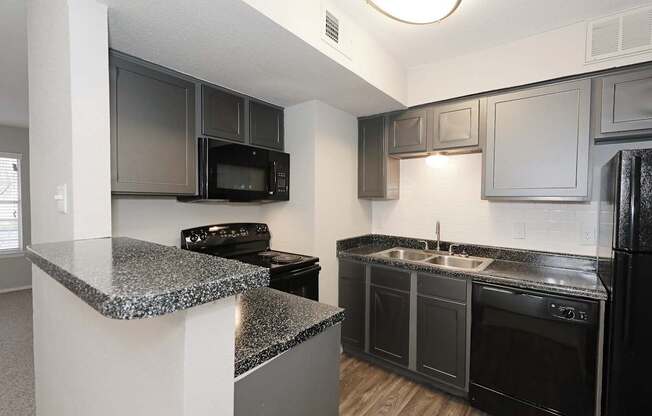 a kitchen with granite countertops and black appliances