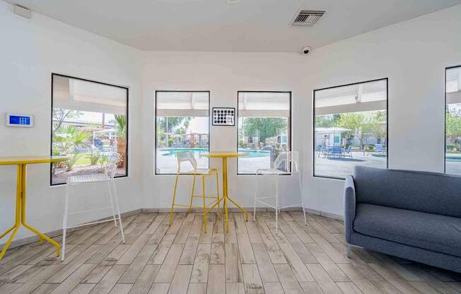 A room with a grey couch, a yellow table, and three framed pictures on the wall.
