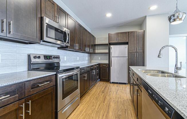 a kitchen with wood cabinets and stainless steel appliances at The Fitzroy San Marcos, Texas