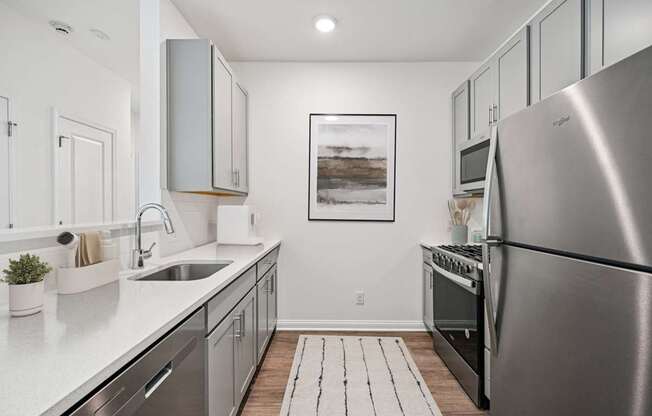 A modern kitchen with a stainless steel refrigerator and a sink with a faucet.
