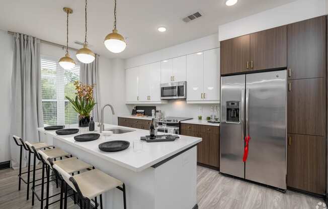 a kitchen with a large island and stainless steel refrigerator