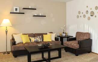 A living room with a brown couch, a black coffee table, and a brown armchair.
