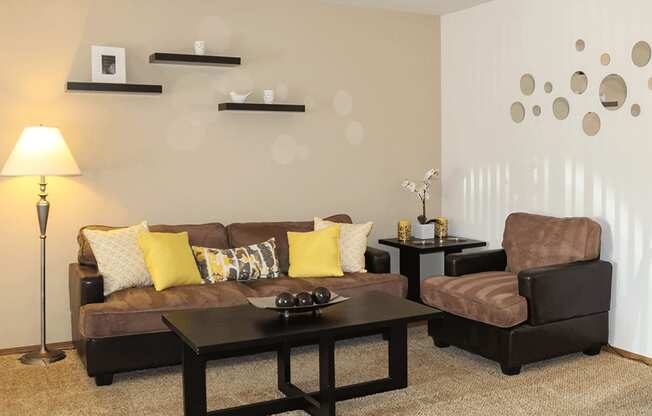 A living room with a brown couch, a black coffee table, and a brown armchair.
