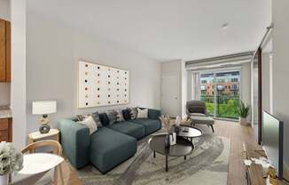 A living room with a grey sofa, a coffee table, a lamp, a painting, and a sliding glass door.