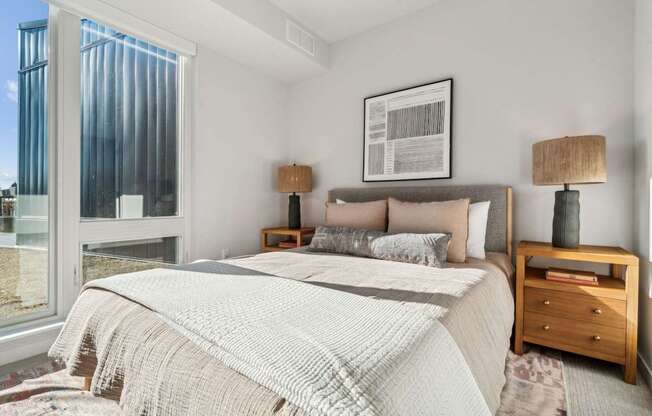 A bedroom with a large bed and a window overlooking a cityscape.